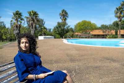 Portrait of young woman sitting on pool