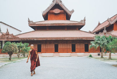 Rear view of man walking on temple against building