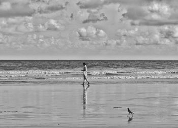Woman walking at sea against sky