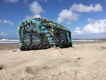 Lobster trap on sandy beach during sunny day