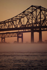 Silhouette cantilever bridge over mississippi river against sky during sunset