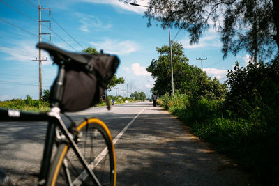 Bicycle on road by trees against sky