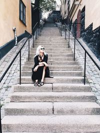 Woman sitting on staircase of building