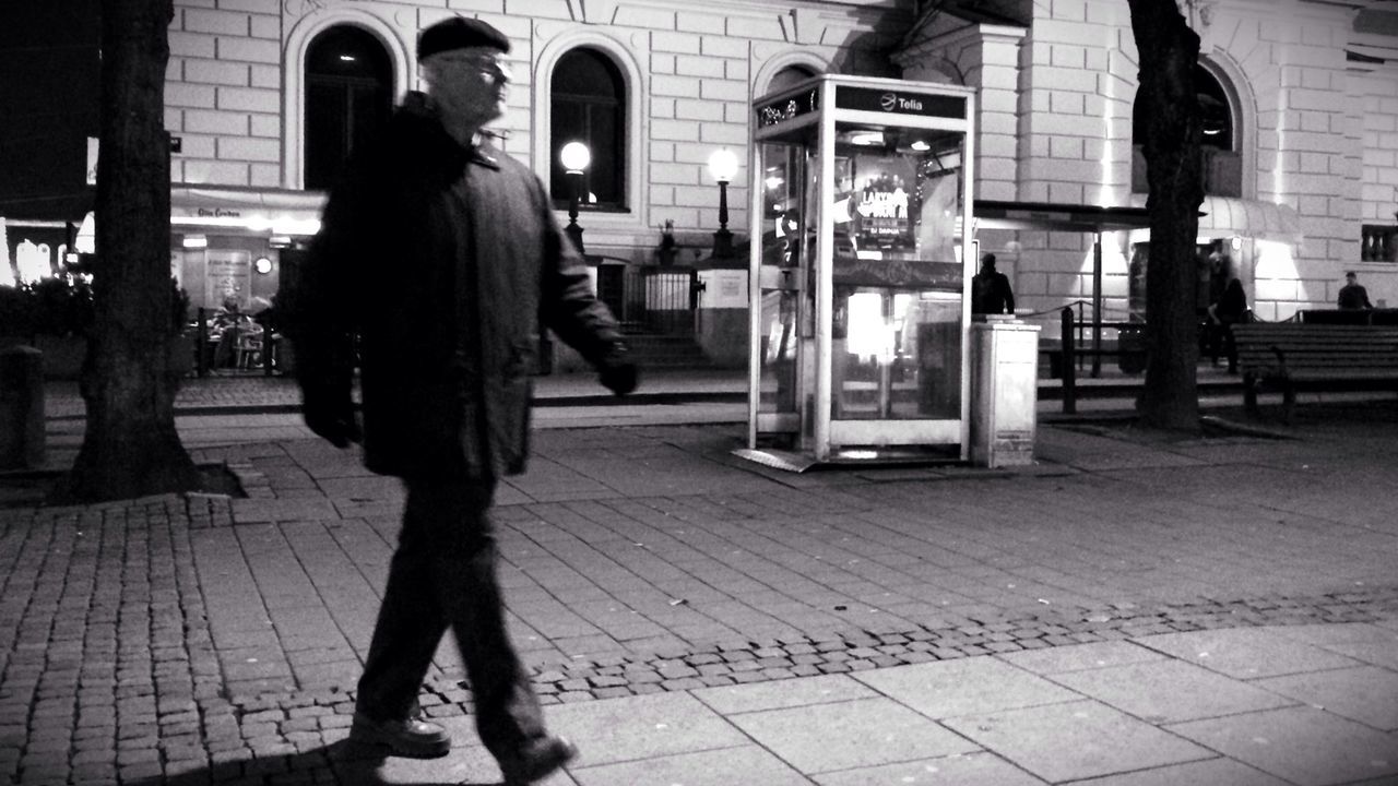 men, street, lifestyles, walking, person, night, city, rear view, city life, sidewalk, standing, low section, leisure activity, building exterior, full length, tiled floor, cobblestone