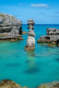 Stack of rocks in sea against blue sky