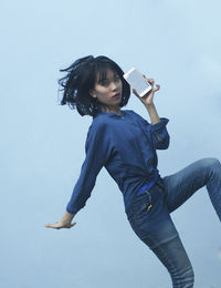 Young woman using mobile phone against clear sky