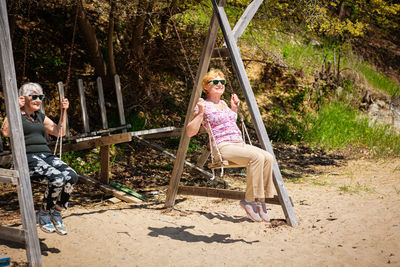 Two elderly women joyfully swinging on a swing