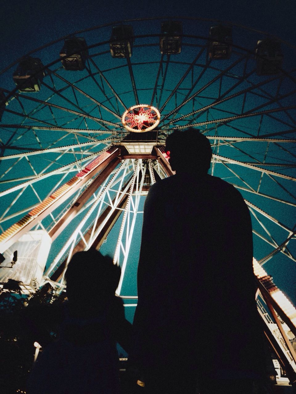 arts culture and entertainment, amusement park, amusement park ride, low angle view, leisure activity, ferris wheel, illuminated, lifestyles, fun, enjoyment, men, night, sky, person, built structure, silhouette, large group of people, traveling carnival, indoors
