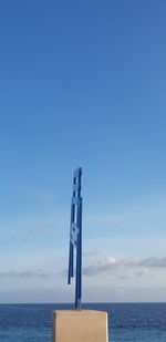 Lifeguard hut by sea against blue sky