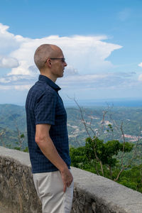 Side view of man standing on rock against sky