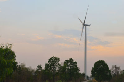 Wind turbines on land against sky during sunset