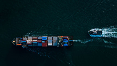 Aerial view container cargo ship and tugboat full speed carrying commercial container import export