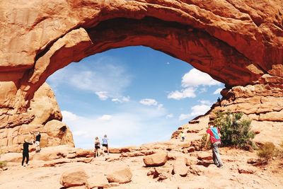 People on rock formation against sky