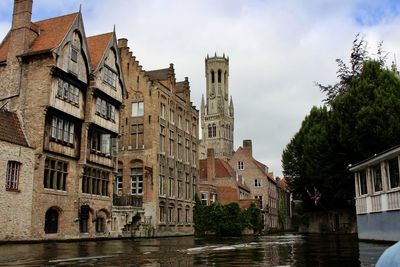 Buildings by river against sky in city