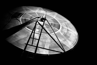 Low angle view of illuminated electric lamp against black background