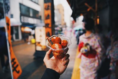 Midsection of man holding ice cream in city