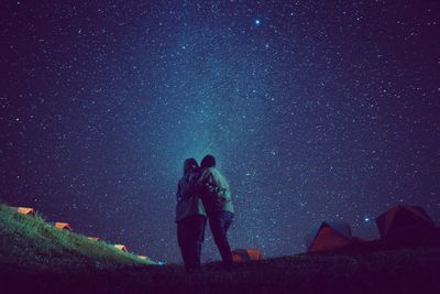 Friends standing against star field at night