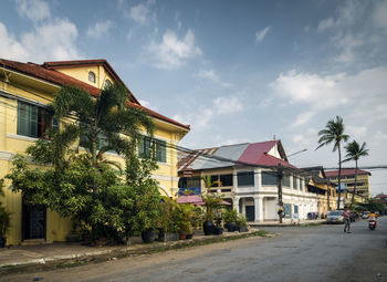 House by palm trees and houses against sky