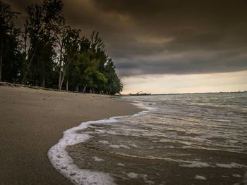 Scenic view of beach against cloudy sky