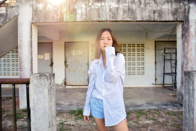 Full length of young woman using phone while standing outdoors