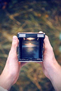 Cropped hands of person holding camera