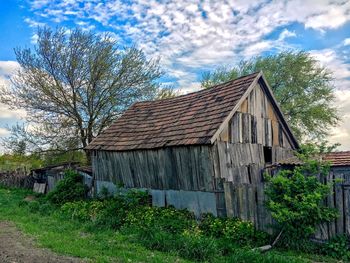 Abandoned barn by tree against sky