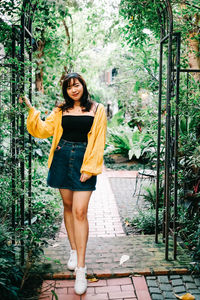 Portrait of young woman standing against plants