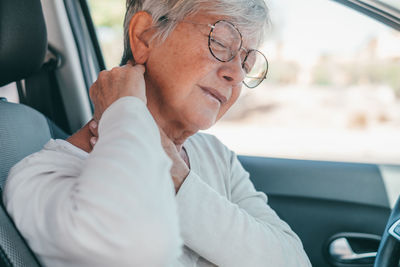 Senior woman having neck ache in car