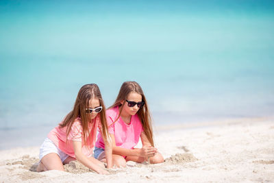 Sisters plying with sand on beach