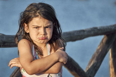 Portrait of sad girl standing against railing