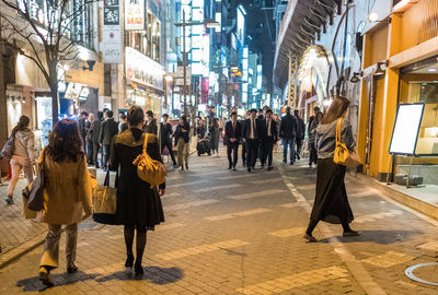 Rear view of people walking on street in city