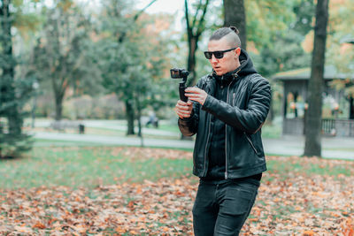 Man holding umbrella standing in park during autumn