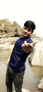 Portrait of young man standing against water