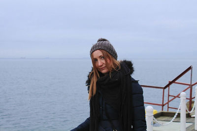 Portrait of mid adult woman standing by sea against sky during winter