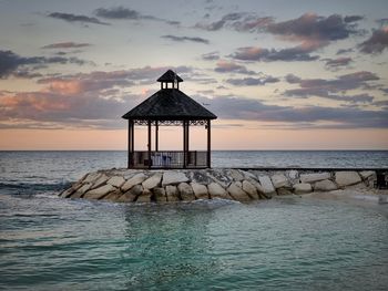 Lifeguard hut by sea against sky during sunset