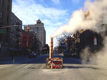 Smoke at construction site on street amidst buildings in city