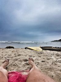 Low section of man on beach against sky