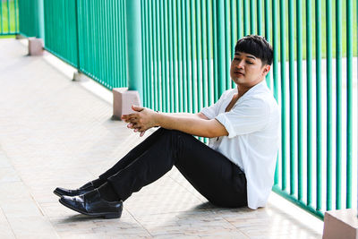 Portrait of man sitting on the floor against wall