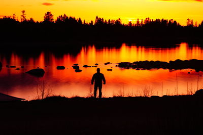 Silhouette people standing on shore against sky during sunset