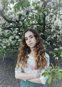 Portrait of beautiful young woman standing against plants