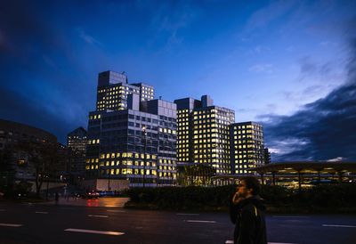 Woman standing in city against sky at night
