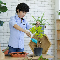 Full length of boy standing on potted plant