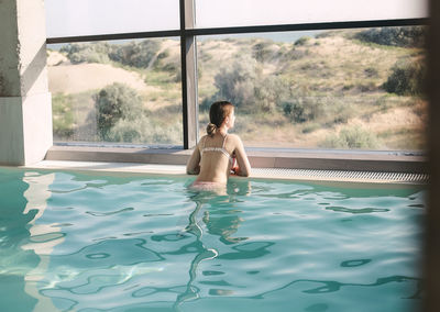 Full length of young woman relaxing in swimming pool