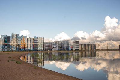 Buildings by river against sky in city