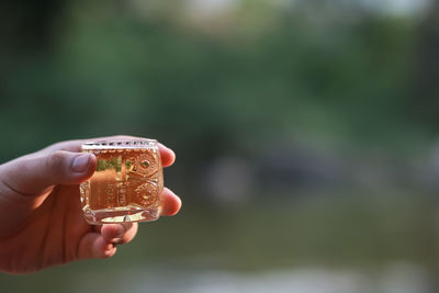 Close up of man hand holding small bubble beer glass against a natural background. drinking beer 