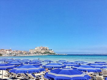 Blue parasols at beach against clear blue sky