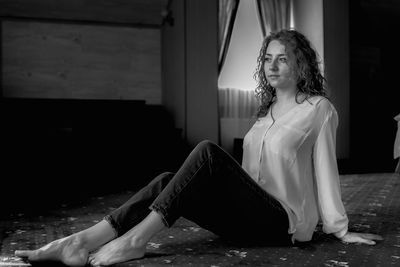 Portrait of young woman sitting on footpath