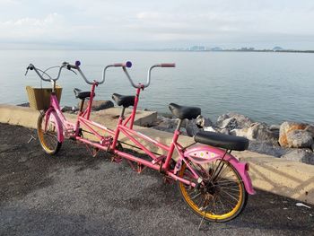Bicycle by sea against sky
