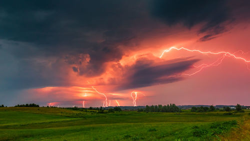 Scenic view of field against dramatic sky during sunset