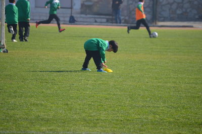 Rear view of men playing soccer on field